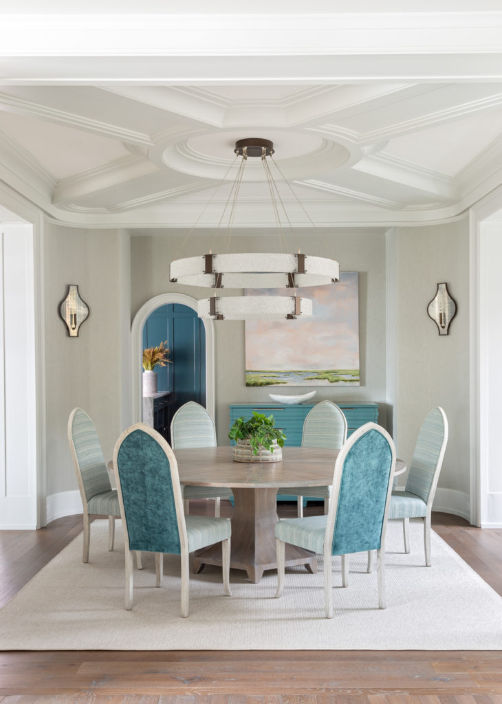 Neutral dining room with round table and deep straight back chairs