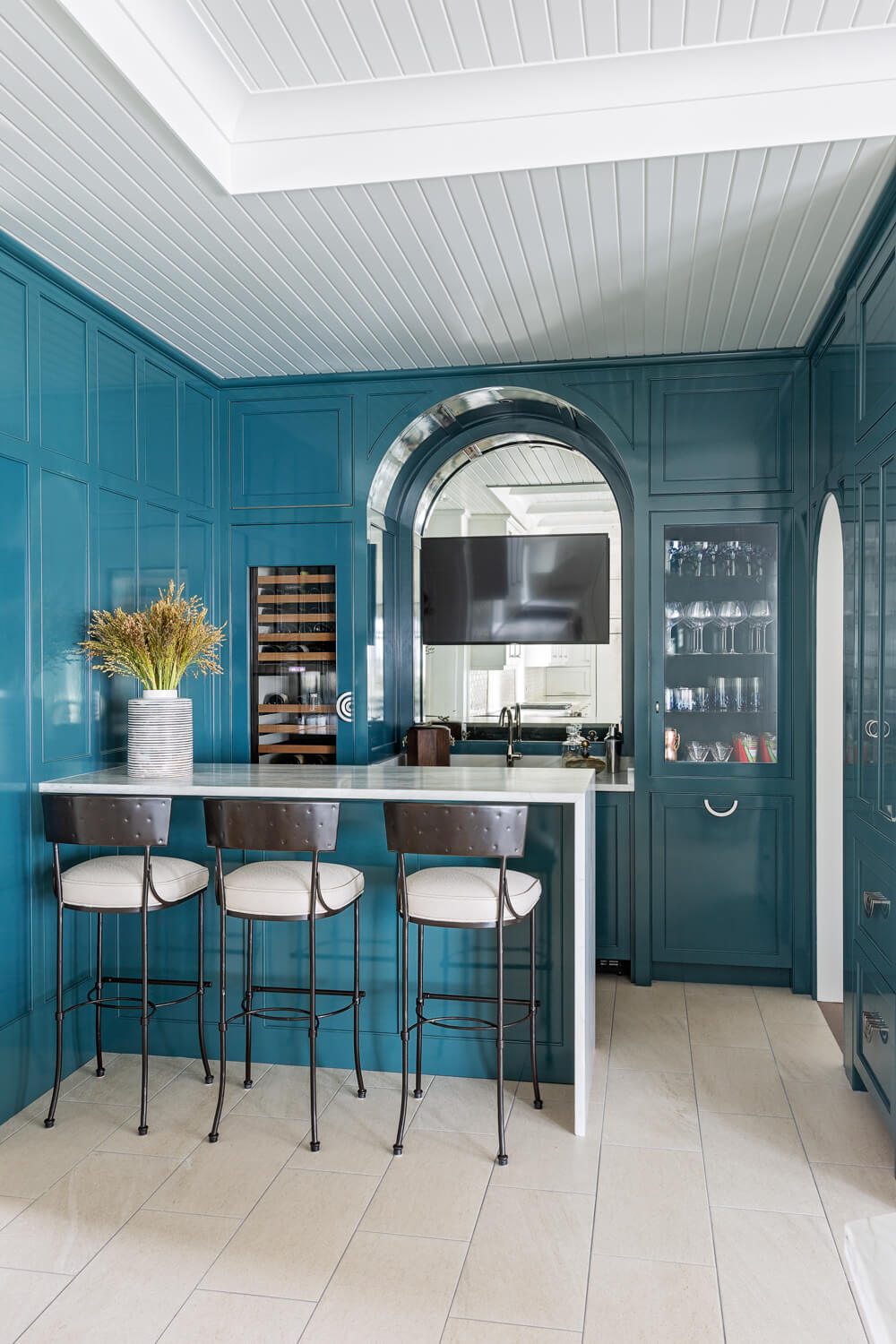 a bar room with white paneled ceiling, teal paneled walls, and a white waterfall countertop