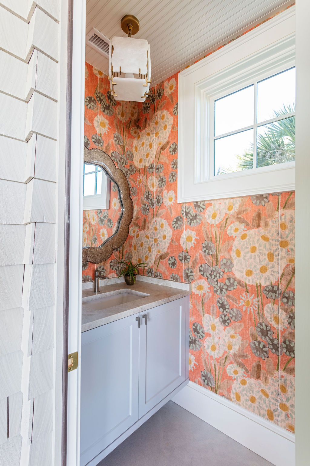 a small Kiawah Island powder room with orange floral wallcovering