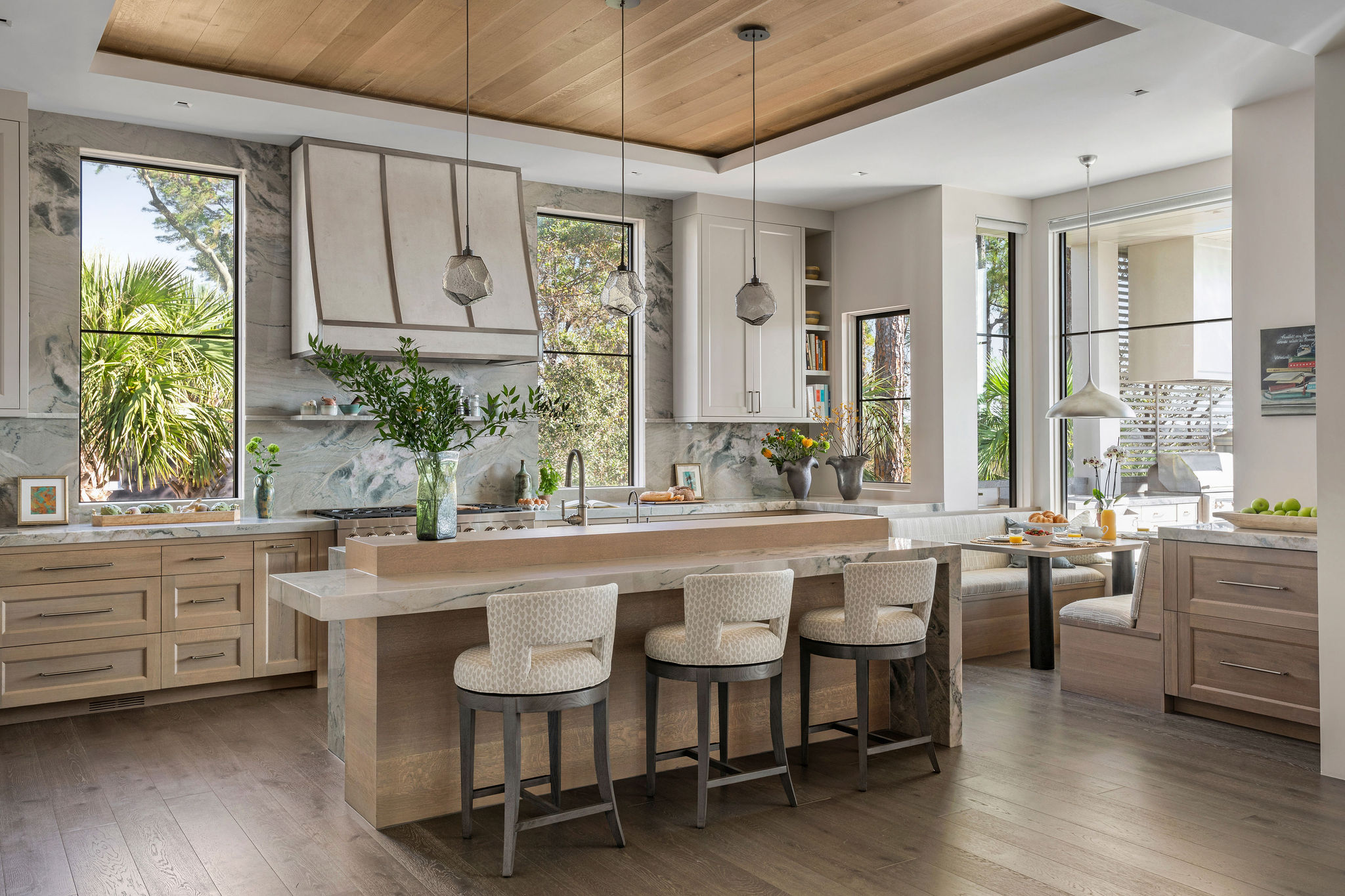 Lowcountry kitchen featuring a cream color palette, light wood tones, picture windows, and a stone backsplash running up the wall